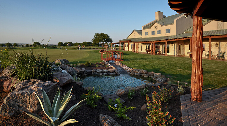 A landscaped pond separates a Hill Country clubhouse from the golf course at Star Ranch.